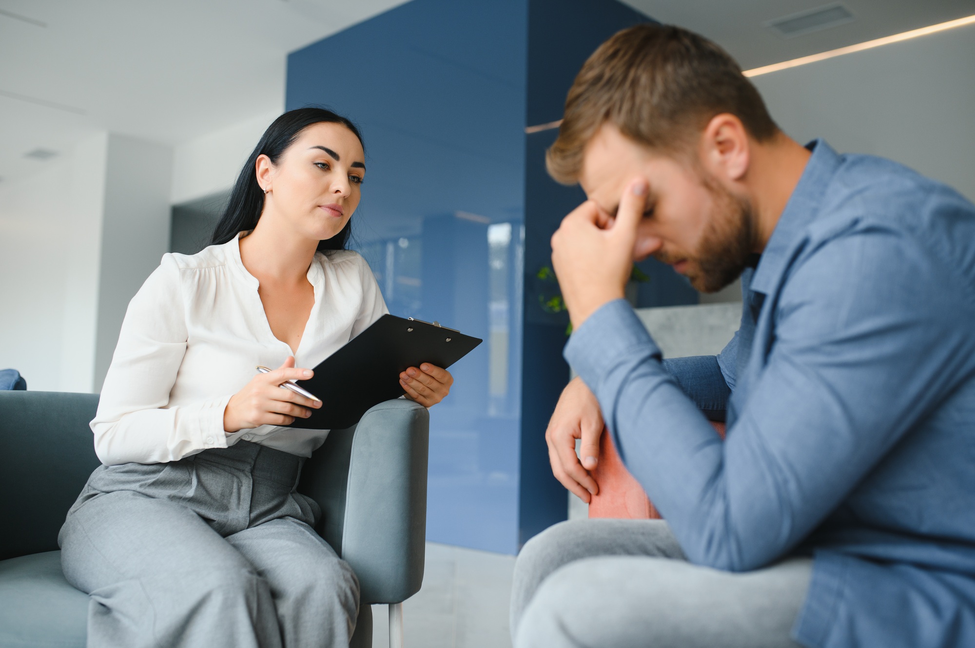 psychology, mental therapy and people concept - woman psychologist talking to sad young man